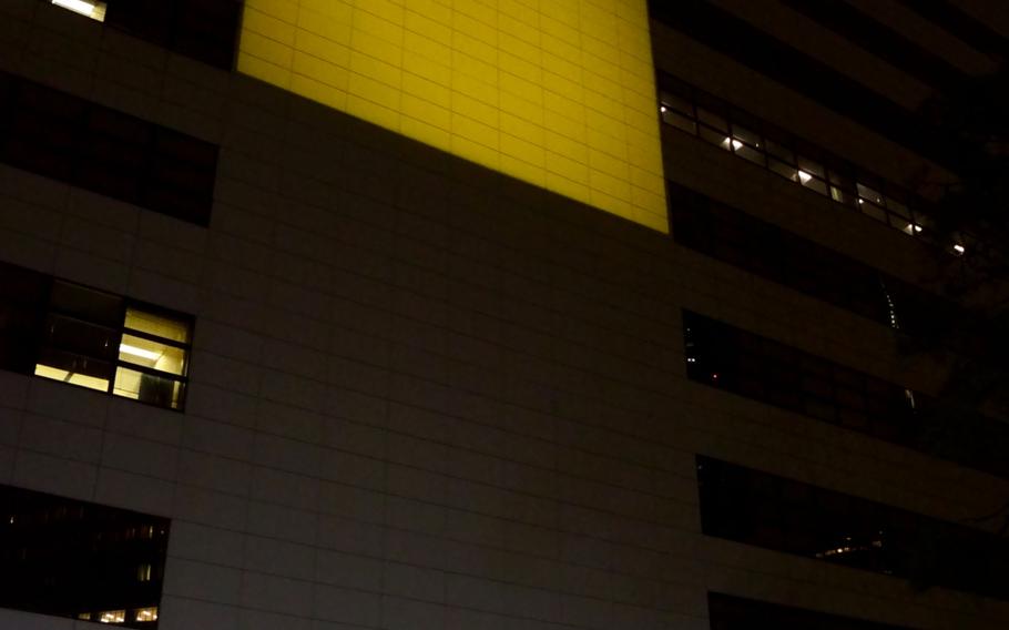 U.S. Ambassador to Japan Rahm Emanuel and his Ukrainian counterpart, Sergiy Korsunsky, stand beneath a Ukraine flag projected onto the U.S. Embassy in Tokyo, Wednesday, March 3, 2022. 