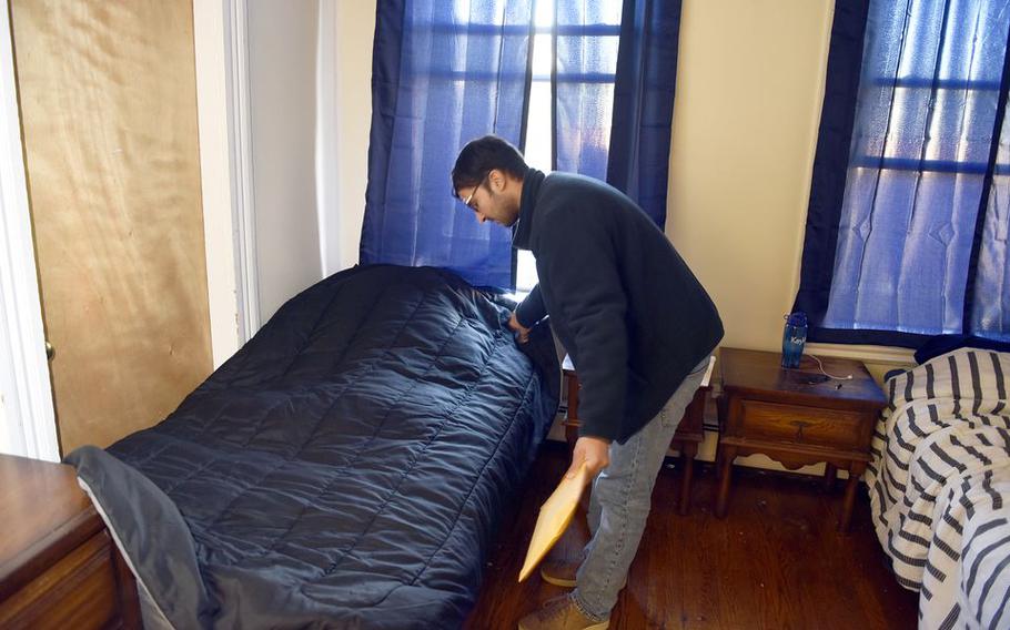 Muhammad Fahim Salimi throws a comforter over his bed in his Northampton, Mass., apartment.  He is one of 68 Afghan evacuees resettled to the Pioneer Valley by Catholic Charities of the Roman Catholic Diocese of Springfield. 