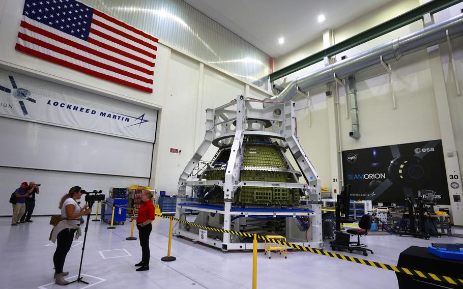 Orion program engineers talk in front of the Artemis III crew capsule being assembled at Kennedy Space Center, Fla., on Sunday, Aug. 28, 2022. The capsule will carry astronauts on a mission to land on the moon in the future.