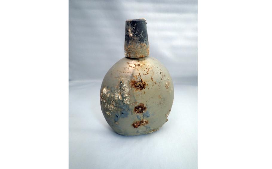 A rusted military canteen, heavily corroded with patches of oxidation and mineral buildup, is shown upright against a neutral background.