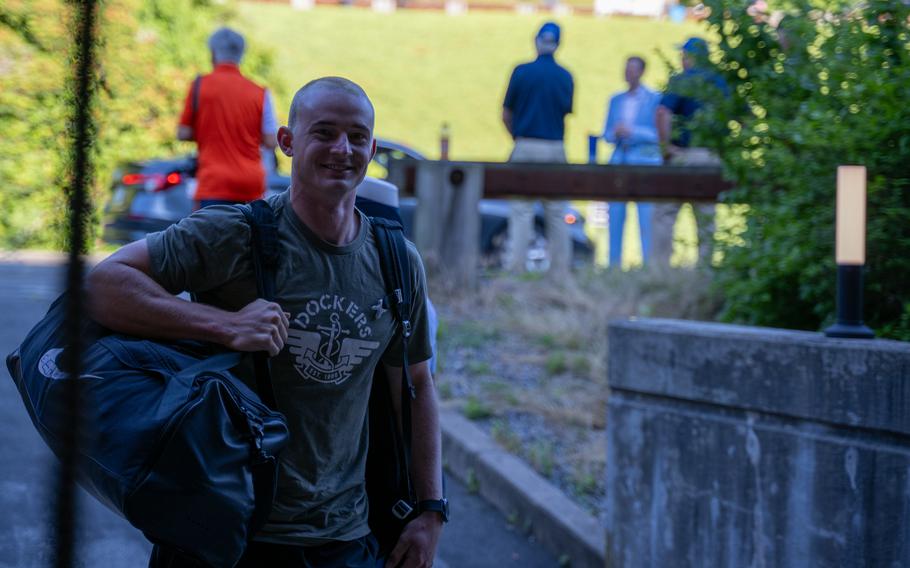 A Coast Guard Academy cadet holds his bag and smiles