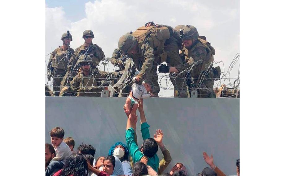 A Marine pulls a baby over the wall at the Kabul airport on Aug. 19, 2021.