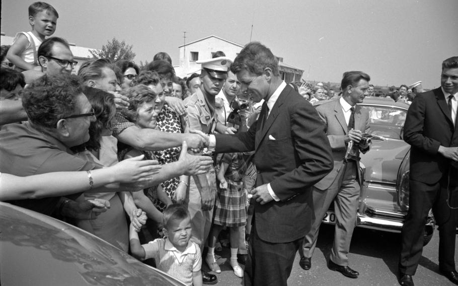 RFK shaking a man’s hand as others around him extend their hands forward.