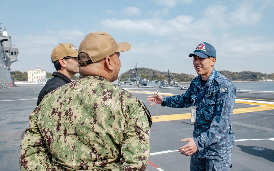 Petty Officers 1st Class Randy Gudelosao, left, and Adrian Gonzales chat with a JS Izumo sailor during a tour of the Japanese carrier in Yokosuka, Japan, April 2, 2024.