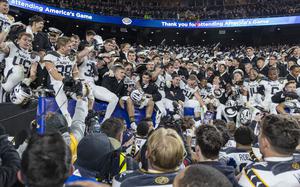 Navy players sit at the edge of the stands.