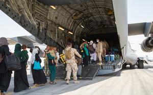 U.S. Marines with the Evacuation Control Center help Afghan evacuees as they board a plane at Al Udeid Air Base, Qatar, Sept. 1, 2021. The Department of Defense is committed to supporting the evacuation of American citizens, Special Immigrant Visa applicants and other at-risk individuals from Afghanistan. (U.S. Marine Corps photo by Lance Cpl. Kyle Jia)