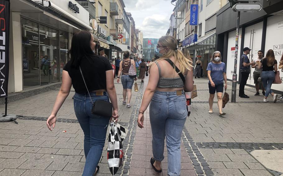 Shoppers, with and without face masks, walk in the pedestrian zone in downtown Kaiserslautern in June 2021, when coronavirus infections were low. In July, as the seven-day average case rate in the city rose above 50 infections per 100,000 residents, officials limited numbers at indoor and outdoor gatherings and required students to wear face coverings in class.