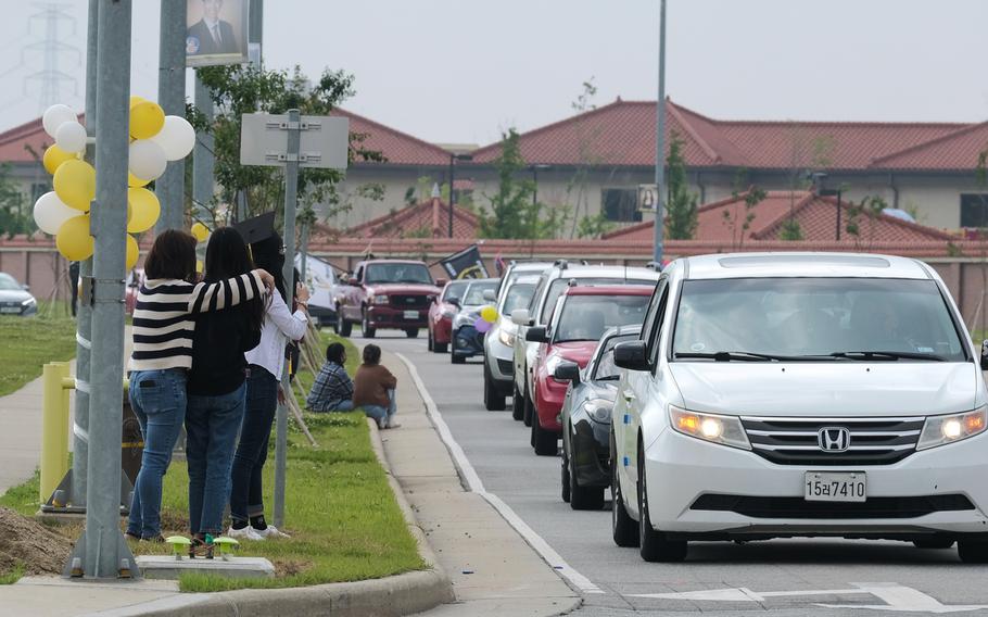 Carfuls of people take part in a reverse parade to congratulate graduating high school seniors lining the streets at Camp Humphreys, South Korea, Thursday, May 27, 2021.