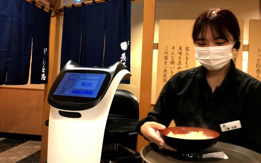 A waitress serves soup with the help of a robot at Totoyamichi, a sushi restaurant near Yokota Air Base, Japan.