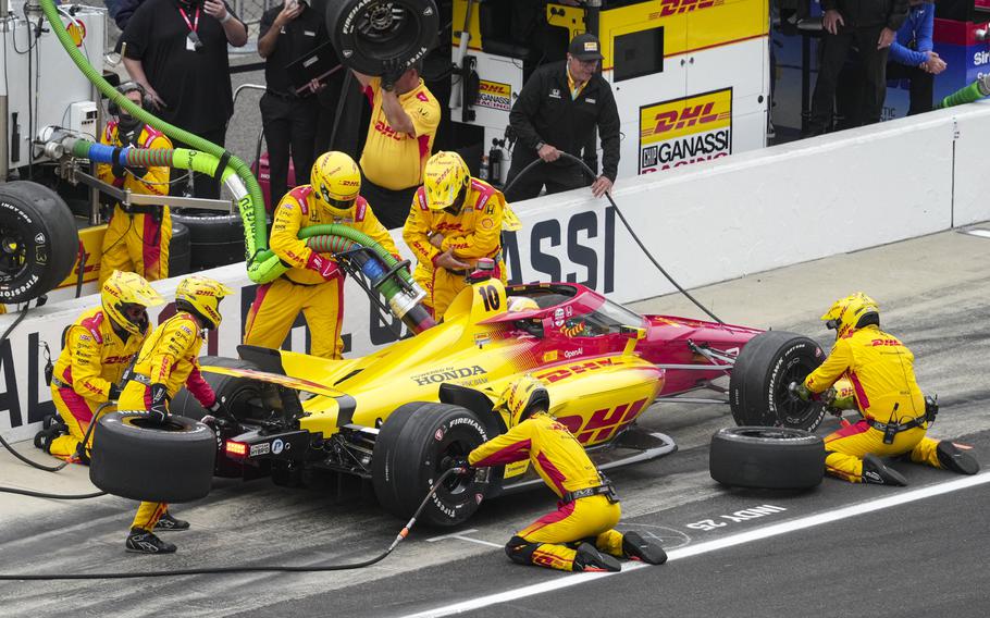 The yellow-clad pit crew changes tires and pumps gas.