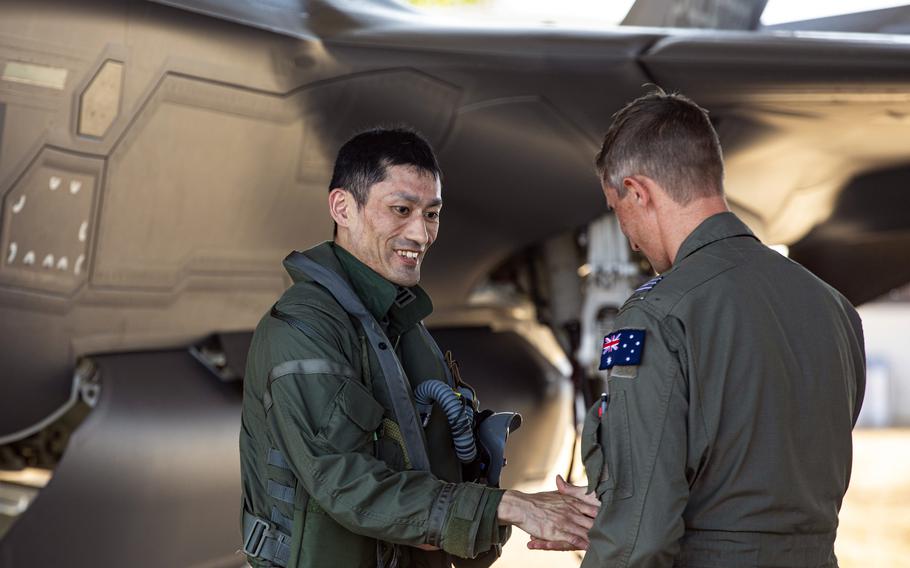 Lt. Col. Kazuhito Okamoto, commander of the Japan Air Self-Defense Force's 301st Squadron, gives a coin to Cmdr. Martin Parker, leader of the No.75 Squadron, at Royal Australian Air Force Base Tindal, Australia, Saturday, Aug. 26, 2023. 