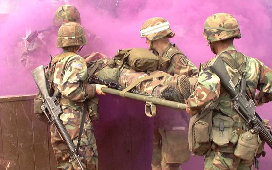 Hed: Expert Field Medical Badge, Kosovo ed., 2002

Camp Bondsteel, Kosovo, Aug. 24, 2002: Medical personnel transport an "injured" soldier through an obstacle course Aug. 22, 2002. As Staff Sgt. Jose Nuques emerges from the smoke, he helps his team carry a patient over a wall. Pictured from left to right are: 1st Lt. Stephanie Martinson, Pfc. Melanie Bauguess (white stripe on helmet) and Staff Sgt. Genaro Silvas. The four were among more than 130 soldiers who attempted to earn the prestigious badge, the first time it has been available to medics and other medical personnel deployed to Kosovo. Om average, only about 15 - 20 percent of each class makes it. 

Read the full account by Kevin Dougherty here. 