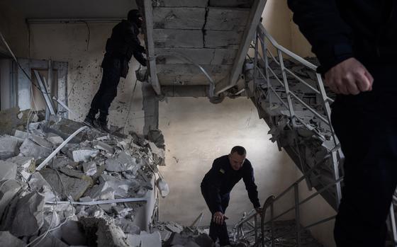 Emergency workers go through a damaged residential building in Kharkiv’s city center on Tuesday. MUST CREDIT: Ed Ram for The Washington Post