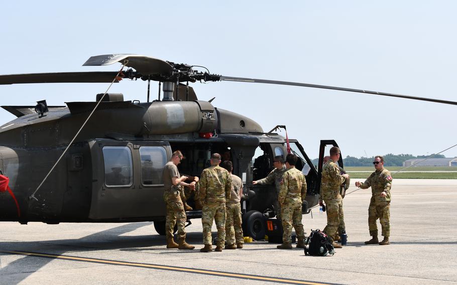 A group of soldiers stand outside a UH-60.