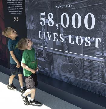 Two young visitors to the USAA Poppy Wall of Honor on the National Mall in Washington, D.C., look at a panel honoring those who were killed in the Vietnam War, May 26, 2023.