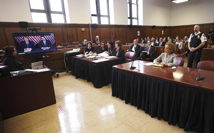 Former president Donald Trump, left on screen, and his attorney, Todd Blanche, right on screen, appear by video, as his other attorney Susan Necheles, right, looks on, before a hearing begins in Manhattan criminal court, in New York, Tuesday, May 23, 2023. Trump made a video appearance Tuesday in his New York criminal case, with the judge tentatively setting a trial date for late March of next year. 