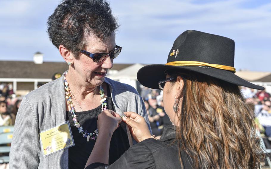 U.S. Air Force retired Col. Regina Aune receives a Vietnam veteran lapel pin from Aryn Lockhart, 17th Training Wing Public Affairs visual information specialist, during the 50th Vietnam War Commemoration at the Fort Concho parade ground in San Angelo, Texas, Nov. 18, 2017. Lockhart was one of the babies from Operation Babylift who survived a plane crash and was adopted and raised in Northern Virginia. In 1997, not long after graduating from Virginia Tech, she began investigating her life story, hoping to write about it. She typed “Operation Babylift” into the nascent Internet and found an article recounting Aune’s heroism, which had resulted in her receiving the prestigious Cheney Award for valor from the Air Force.