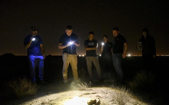 Troops and contractors at Ali Al Salem Air Base in Kuwait gather around a suspected hideout for scorpions while searching for critters on Nov. 28, 2022.