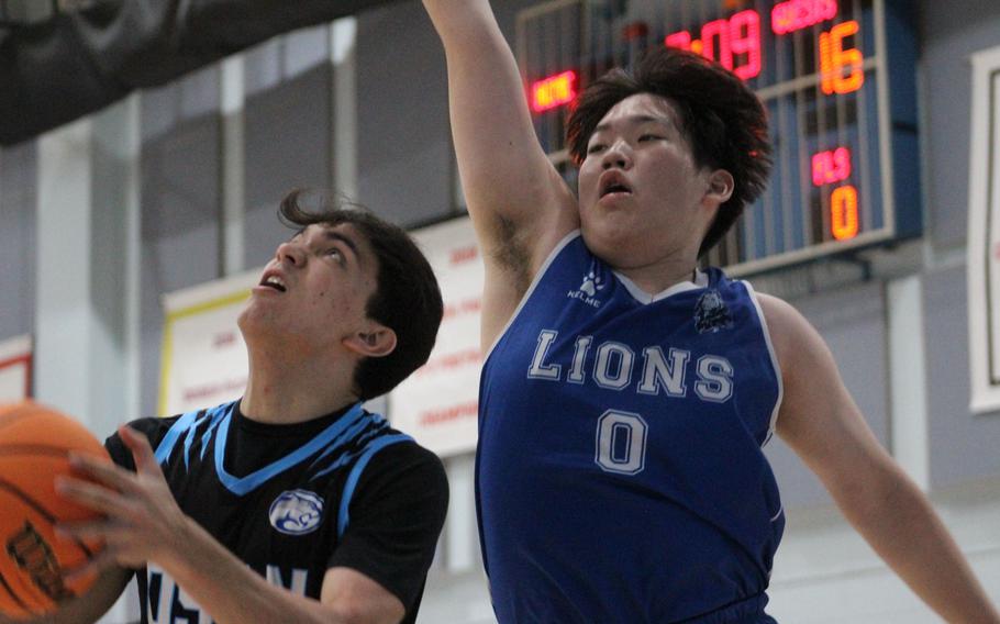 Osan's M.J. Siebert looks for room against Dwight School of Seoul's William Wong, during Friday's Korea boys basketball game. The Lions won 50-42.