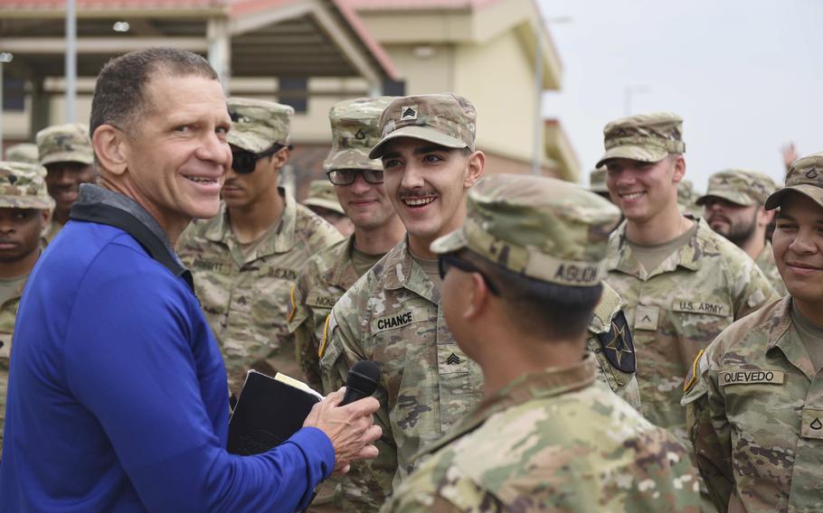 Michael Grinston, wearing a bright blue shirt, is surrounded by uniformed soldiers at a U.S. base in South Korea.