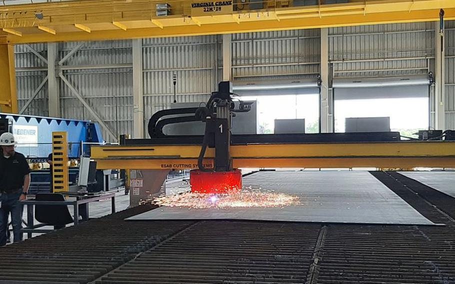 A plasma cutter at Austal USA makes the "first cut" in plating that will become part of the Mobile shipyard's first steel ship, a Navajo-class towing, salvage and rescue ship built for the U.S. Navy.