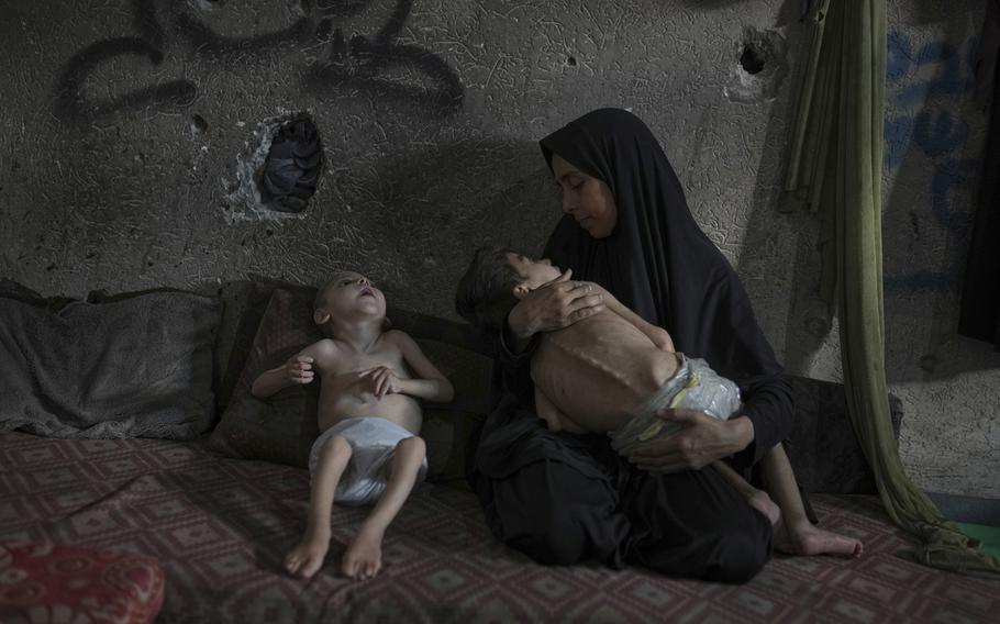 Samah Matar poses for a photo with her sons Yousef, 6, in her arms, and Amir, 4, who suffer from malnutrition and cerebral palsy, at a U.N.-run school in Gaza City, Saturday, July 26, 2025.