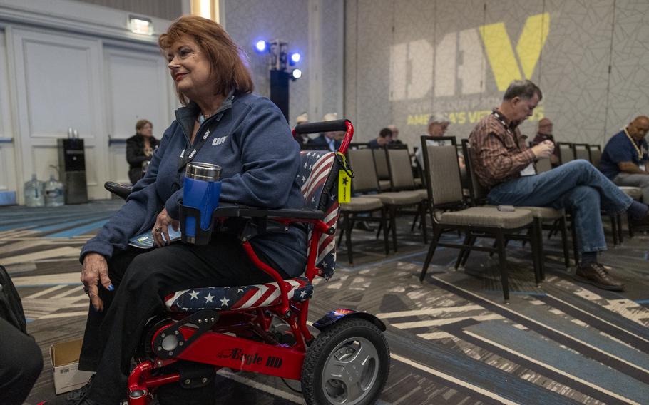 A woman sitting in a wheelchair with red, white and blue cushions.