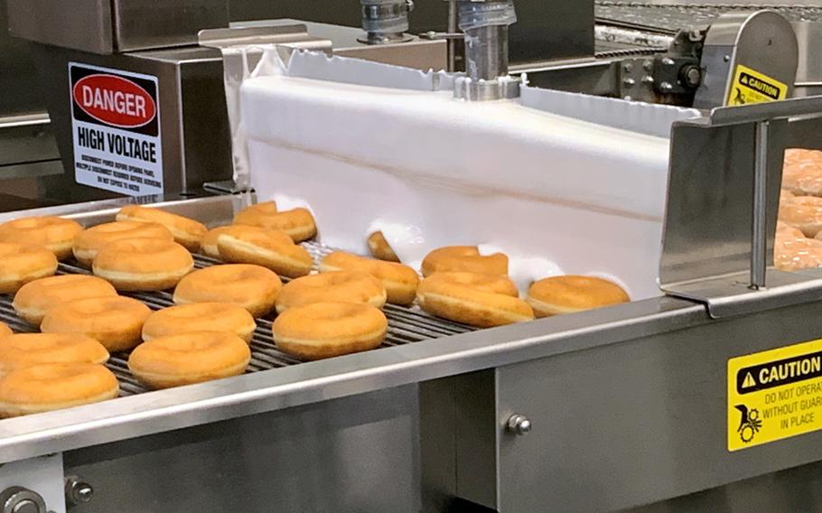 Fresh Krispy Kreme doughnuts are glazed at a new Army and Air Force Exchange Service bakery and distribution center at Camp Humphreys, South Korea, Friday, Nov. 19, 2021.