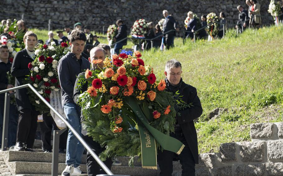 A group of people walk a wreath down the stairs together