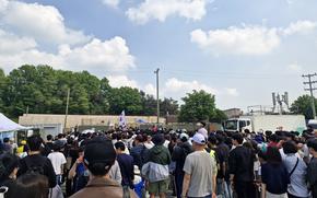 A crowd gathers at an Osan Air Base festival with a blue sky and fluffy white clouds in the background. 