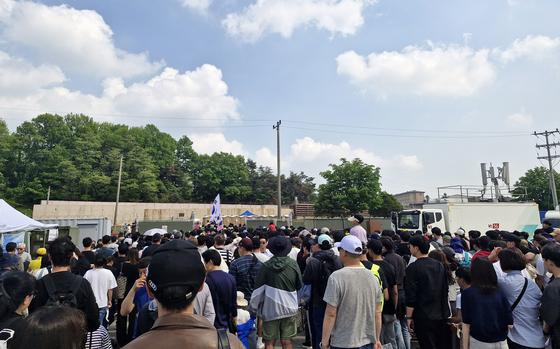 A crowd gathers at an Osan Air Base festival with a blue sky and fluffy white clouds in the background. 