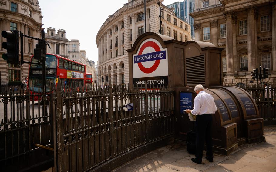 A pedestrian looks at a newspaper near the entrance to Bank London Underground station, on so-called "Freedom Day" in London on July 19, 2021. 