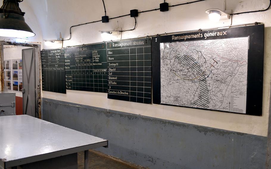 Museum wall display featuring military intelligence boards with French text including “Renseignements généraux” (General Intelligence), showing charts, maps, and operational information from wartime.