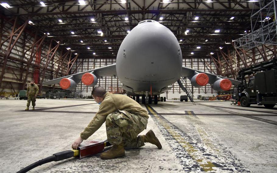 United States Air Reserve Tech Sgt. Kevin Godek of Palmer attaches a power supply to a C-5M Super Galaxy as he works in a maintenance hangar at Westover Air Reserve Base in Chicopee, Mass.  