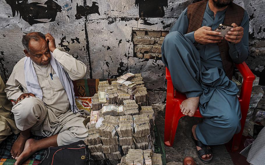 Money exchangers organize their stacks of Afghan currency and await customers at the Sarai Shahzadah, Kabul’s currency exchange market, in Kabul, Afghanistan, on Sept. 7, 2022. 