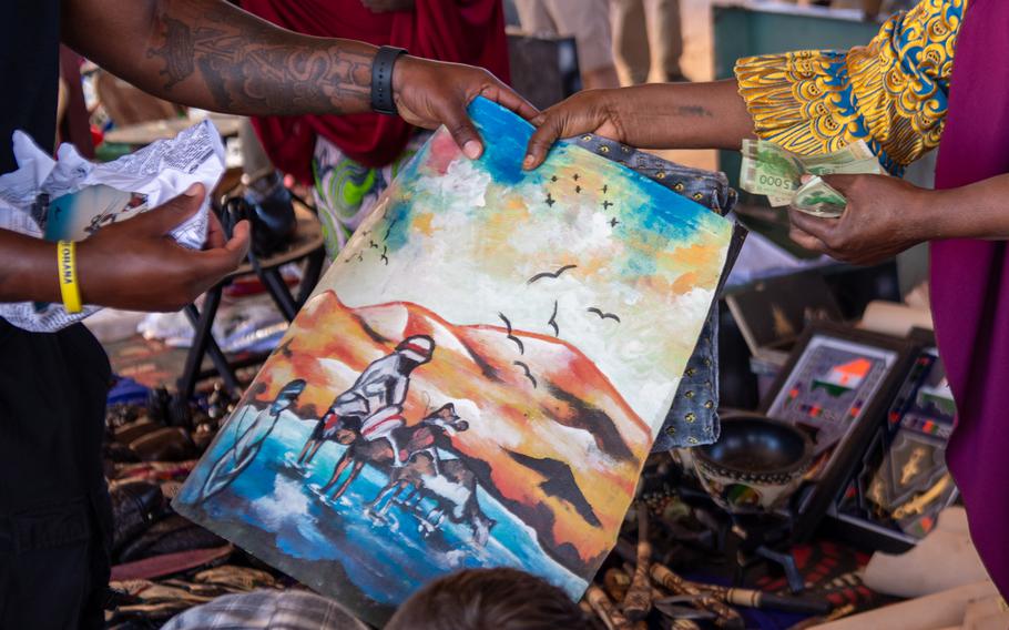 A U.S. service member purchases a painting from a local vendor  Dec. 2, 2023, at the women’s bazaar at Base 201 in Agadez, Niger. The event drew 24 female vendors, who sold more than 750 items.