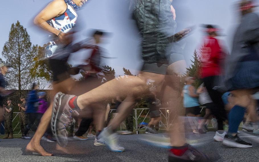 A runner, left, runs barefoot during the 2024 Marine Corps Marathon