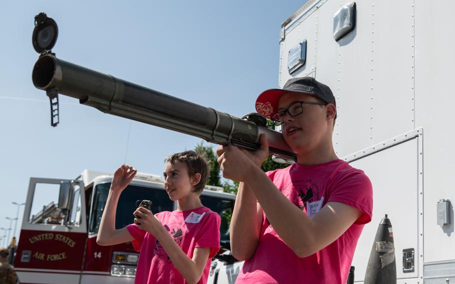 A boy wearing a baseball cap holds an unloaded anti-tank missile launcher and another holds an inert grenade.