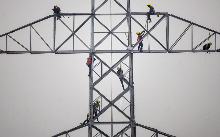 Technicians work on an unconnected transmission tower.