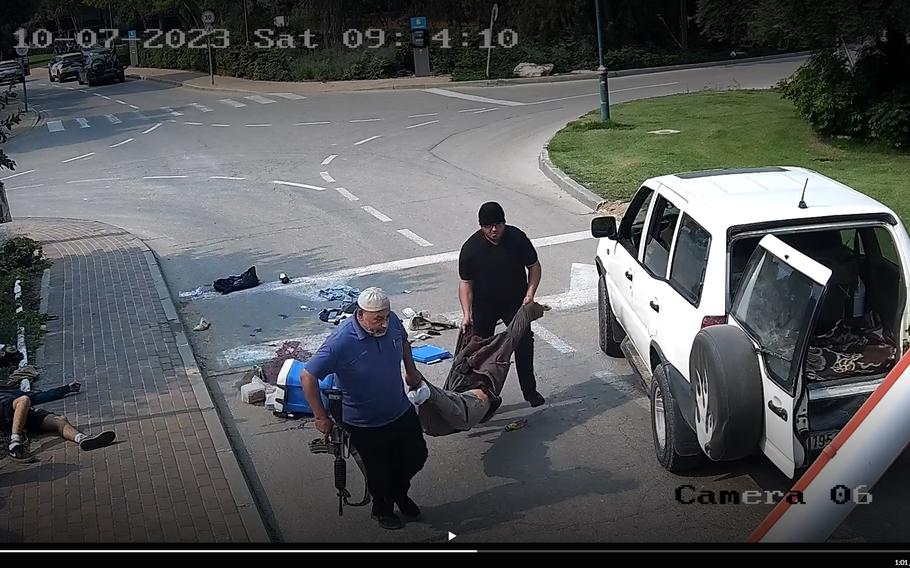 A video screen grab shows a man identified as Faisal Ali Musalam Naami (seen in black), whom Israel alleges is a United Nations Relief and Works Agency member seen Oct. 7, 2023, as he and another man carry the limp body of an Israeli man who had been shot at Kibbutz Beeri. The two then stuff the body in the back of a vehicle before driving off.