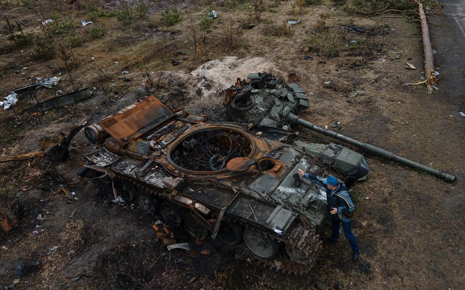 In questa immagine aerea, un uomo mette uno stivale per scattare una foto di un carro armato militare russo distrutto il 21 aprile 2022 a Dmytrivka, in Ucraina.