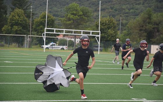 A small parachute trails behind Aviano's Gabe Wood as he sprints along with teammates at the first day of fall practice at the school Monday, Aug. 4, 2025.

Kent Harris/Stars and Stripes