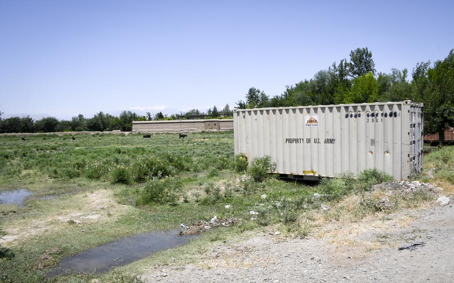 A shipping container that belonged to the U.S. Army sits in a field near cows at a farm outside of Bagram Airfield, Afghanistan. A surge of containers and junk have been trucked out of Bagram since May, residents near the base said June 5, 2021. 