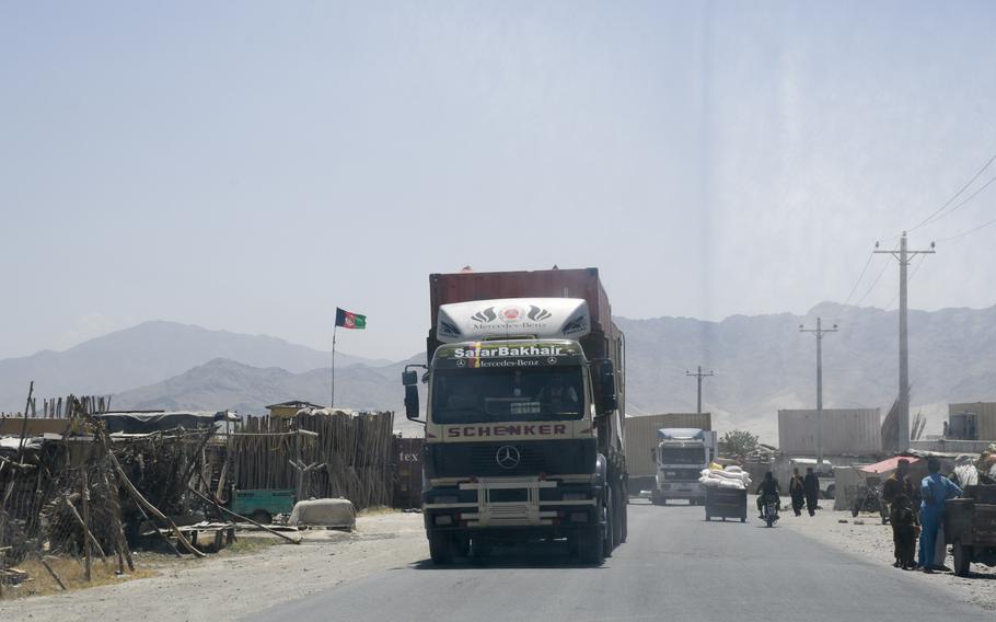 A line of trucks drives out a gate at Bagram Airfield, Afghanistan on June 5, 2021. A surge of containers and junk have been trucked out of Bagram since May, residents near the base said. 