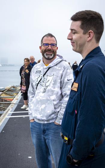 A sailor and a man stand and talk together