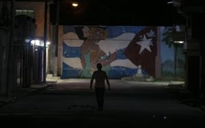 A pedestrian walks down a street during a rolling blackout in Havana on March 26. Frustration with the economic crisis prompted rare protests this month. MUST CREDIT: Yander Zamora/Bloomberg