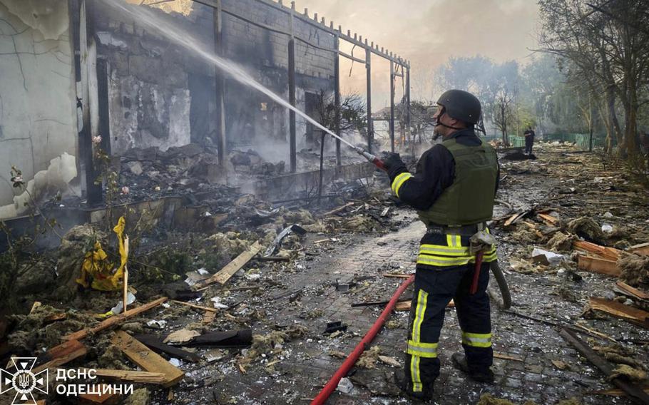 An emergency responder sprays a hose at a destroyed building.