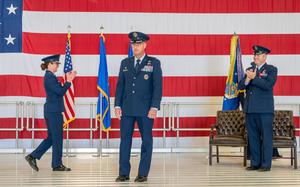 Two Air Force members applaud a third as he walks across a stage.