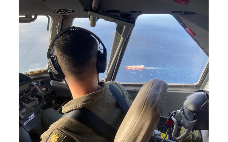 U.S. Coast Guard pilot Lt. Cmdr. Joshua Mitcheltree flies a C-144 Ocean Sentry above the Florida Straits on Jan. 14, 2023, as a cargo ship sails on the water below. 
