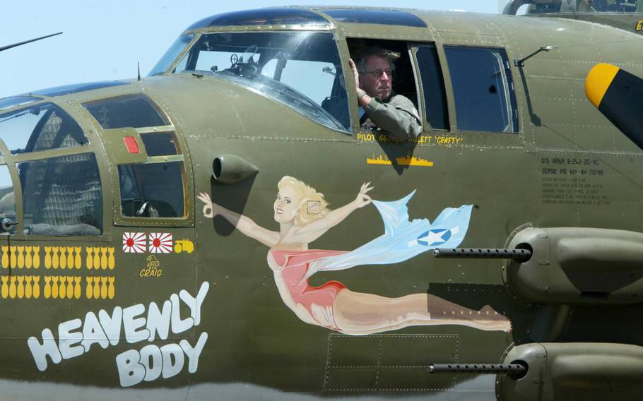 A man sits in the pilot’s seat of an aircraft and looks out the window
